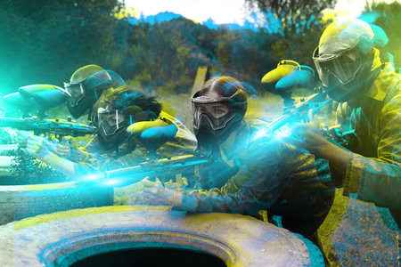 Group of people in full gear playing paintball on shooting range outdoorの写真素材