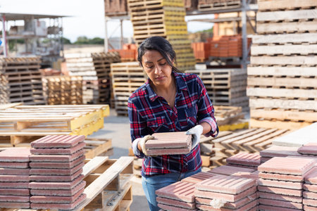 Female warehouse employee puts paving slabs on palletの写真素材