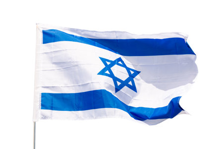 National flag of Israel flies on flagpole against blue skyの写真素材