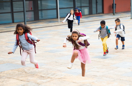 Tween boys and girls with school backpacks running in schoolyardの写真素材