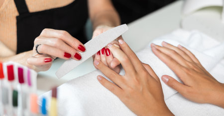 Woman nail technician performing professional manicure for young female clientの写真素材