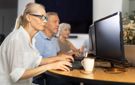 Focused senior woman in glasses attending group computer class