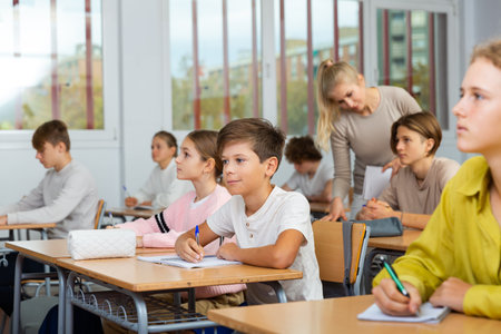 Teenagers sitting at desks in classroom during lessonの写真素材