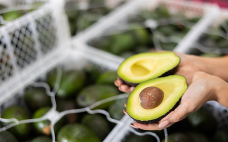 Farmer woman holding cut ripe hass avocado in handsの写真素材