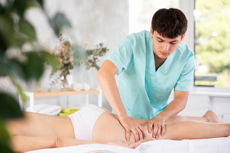 Young guy massages thighs of adult womanの写真素材