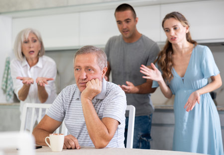 Portrait of thoughtful elderly man who had conflict with his wife and adult children while cooking dinner in kitchenの写真素材