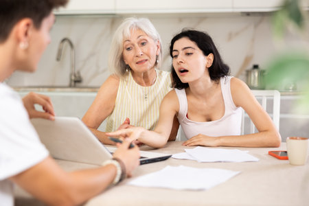 Male insurance agent offers the best insurance terms for an elderly woman and her adult daughter.の写真素材