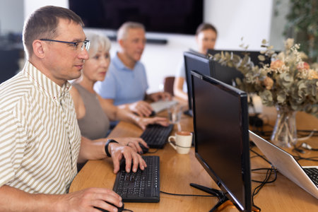 Male teacher teaching elderly people how to use computerの写真素材