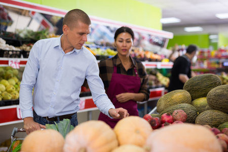 Man looking for ripe fruits and vegetables in supermarketの写真素材