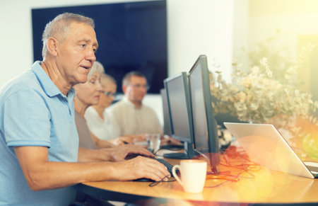 Elderly man studying at computer course in groupの写真素材