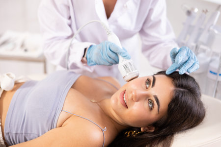 Young brunette undergoing hardware facial treatment using cold hammer