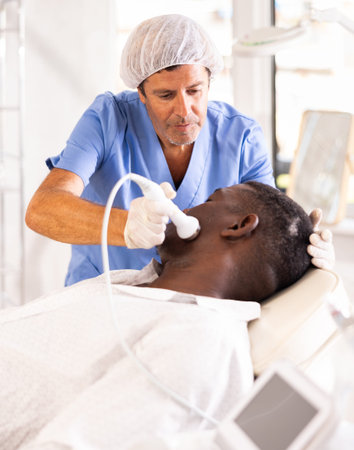 Professional aesthetician administering high frequency ultrasound facial procedure on man