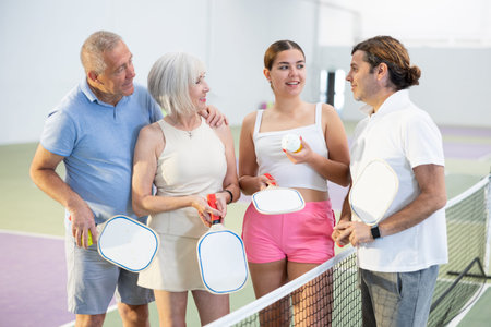 Group of pickleball players are actively discussing past game on court