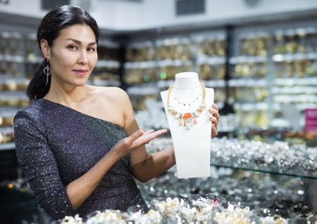 Seller demonstrates differnt necklace in storeの写真素材