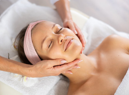 Young woman client gets procedure of rejuvenating massage face skin on cosmetologist visitの写真素材