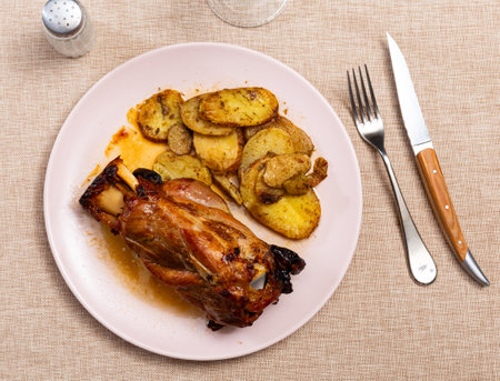Pork knuckle baked in oven with boiled potatoes in white plateの写真素材