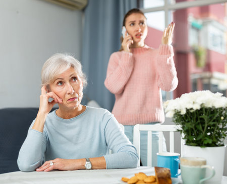 Senior woman listening her daughter aggressively talking on phoneの写真素材