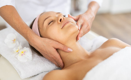 Young female client receiving soothing and relaxing facial massageの写真素材