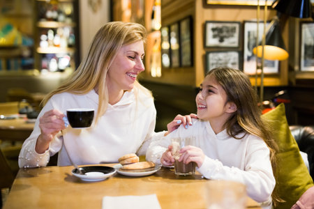 Portrait of happy mother and teenage daughter drinking tea in cafeの写真素材