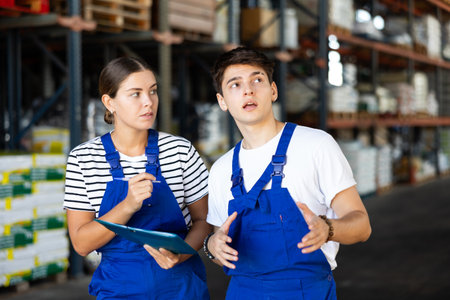 Young woman and young guy warehouse workers checking documentsの写真素材
