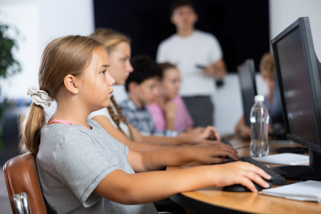 Preteen girl working with computer programs in training roomの写真素材