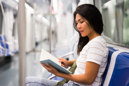 Woman reading book in subway trainの写真素材