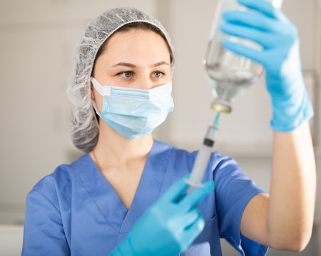 Girl nurse in mask holding syringe for injection in clinicの写真素材