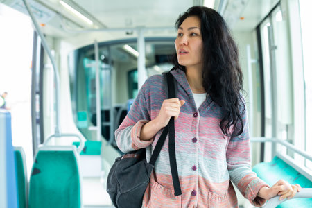 Asian woman with backpack sitting on seat inside tram at dayの写真素材