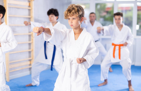 Preteen attendee of karate classes practicing kata standing in row with othersの写真素材