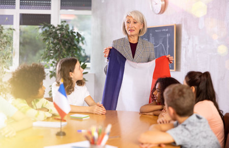 Female teacher showing french flag to kids in geography classの写真素材