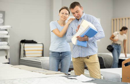Married couple chooses and discusses mattress filling in furniture storeの写真素材