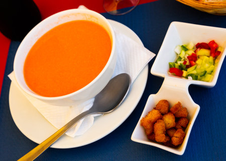 Cold gazpacho soup in a bowl, served with baked bread and vegetablesの写真素材