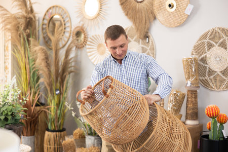 Male shopper in furniture center chooses new wicker laundry basketの写真素材