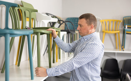 In furniture store, man considering choose chairs for completing office suiteの写真素材