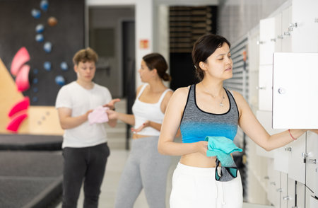 Woman in locker room putting clothes in drawer after workout at climbing wallの写真素材