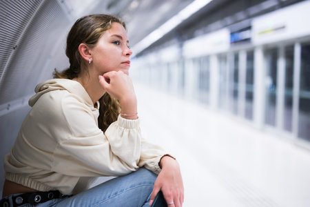 Young attractive girl in jeans waiting for subway train on a platformの写真素材