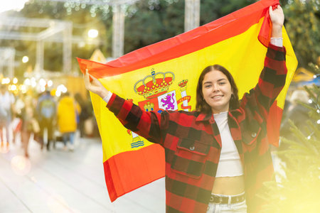 Cheerful girl with flag of Spain at Christmas city marketの写真素材