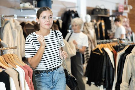 Girl buyer noticed desired product in clothes store and happily smiles from upcoming purchaseの写真素材