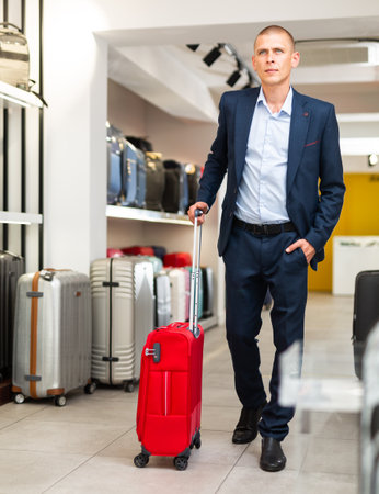 Positive man chose suitcase in haberdashery storeの写真素材