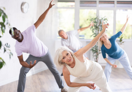 Active mature men and women practicing Jazz-funk dance in training hallの写真素材