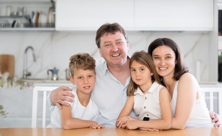 Parents posing with their two little children by the table in the kitchenの写真素材