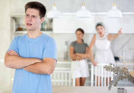 Upset guy dont speaking with mother and wife standing behindの写真素材