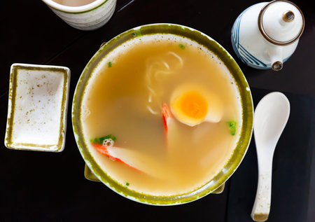 Traditional japanese noodle soup with mushroom, egg and greens served in bowl