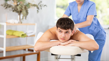 Female masseuse makes relaxing massage shoulder zone to man in beauty parlorの写真素材