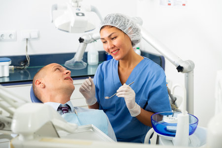 Dentist inspects male patient teethの写真素材