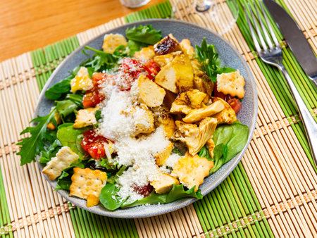 Caesar salad with chicken pieces, croutons, tomatoes, lettuce and parmesan cheeseの写真素材