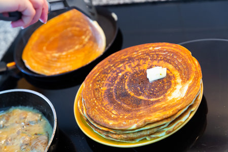 Cook fries thin pancakes in frying pan and places them on plateの写真素材