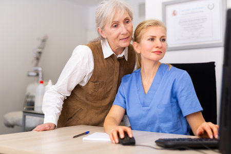 Young woman dermatologist using computer with patient during appointmentの写真素材