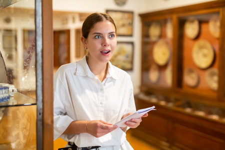 Woman visiting sculpture hall in museum and looking at exhibitsの写真素材
