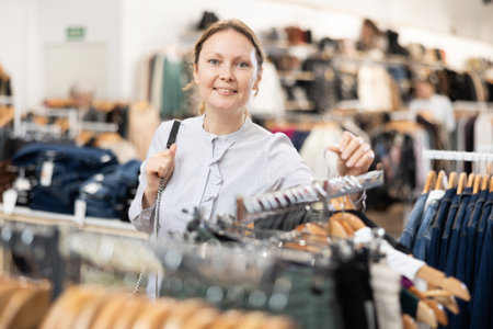 Middle-aged woman watching excitedly large stock of clothes in clothing storeの写真素材